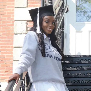 Photo of Leah Rose outdoors wearing a graduation cap.